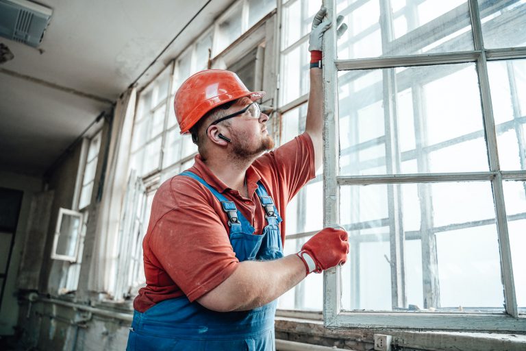 Concentrated builder working with a glass window at a construction site